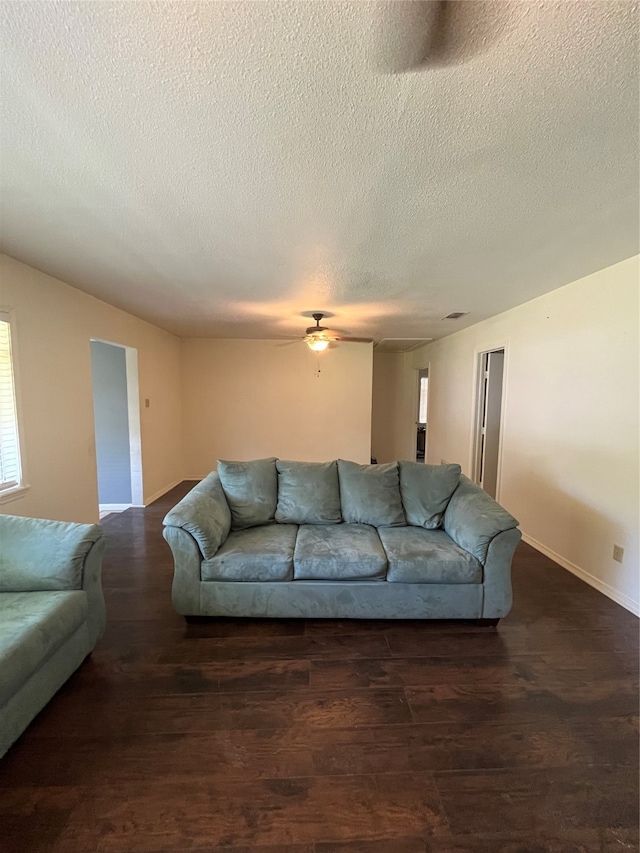 living room featuring a textured ceiling, dark wood-type flooring, and ceiling fan