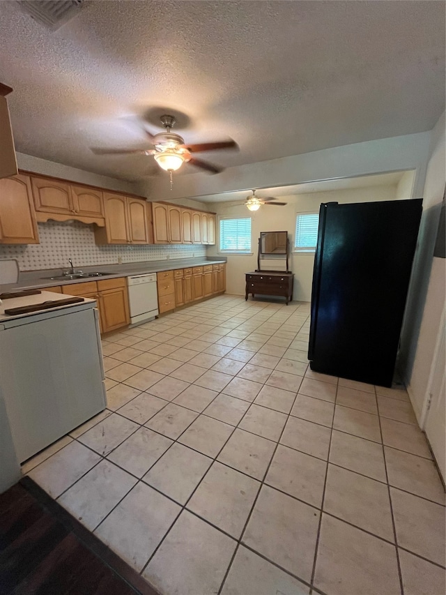 kitchen featuring white dishwasher, stove, black refrigerator, and light tile patterned flooring