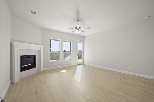 unfurnished living room with ceiling fan, light wood-type flooring, and a tile fireplace