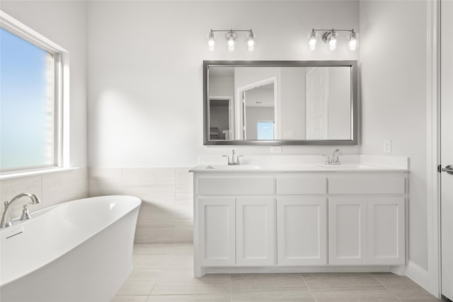 bathroom with tile patterned flooring, vanity, tile walls, and a bathing tub