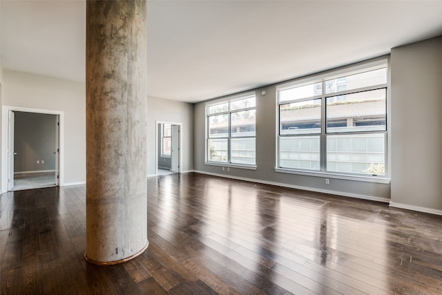 empty room featuring ornate columns and dark hardwood / wood-style flooring