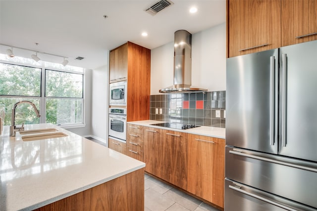 kitchen featuring wall chimney range hood, sink, light tile patterned flooring, appliances with stainless steel finishes, and tasteful backsplash