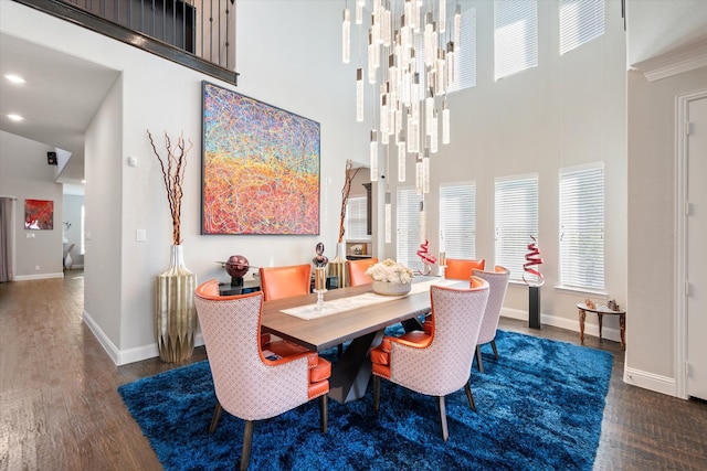 dining area featuring ornamental molding, a high ceiling, and dark wood-type flooring