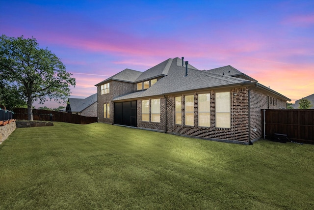 back house at dusk featuring a yard