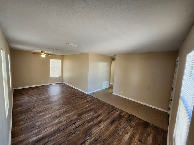 empty room with ceiling fan, a textured ceiling, and dark hardwood / wood-style floors