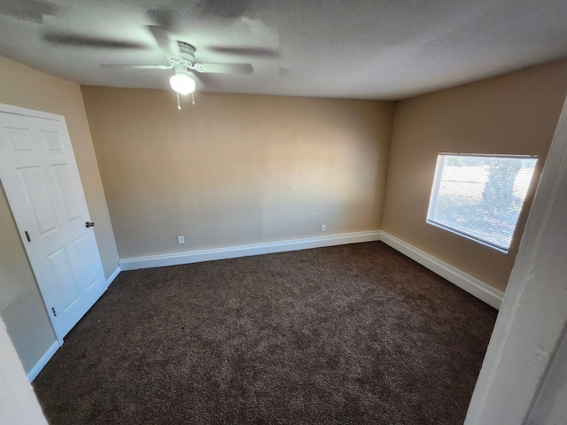 empty room with dark colored carpet, a textured ceiling, and ceiling fan