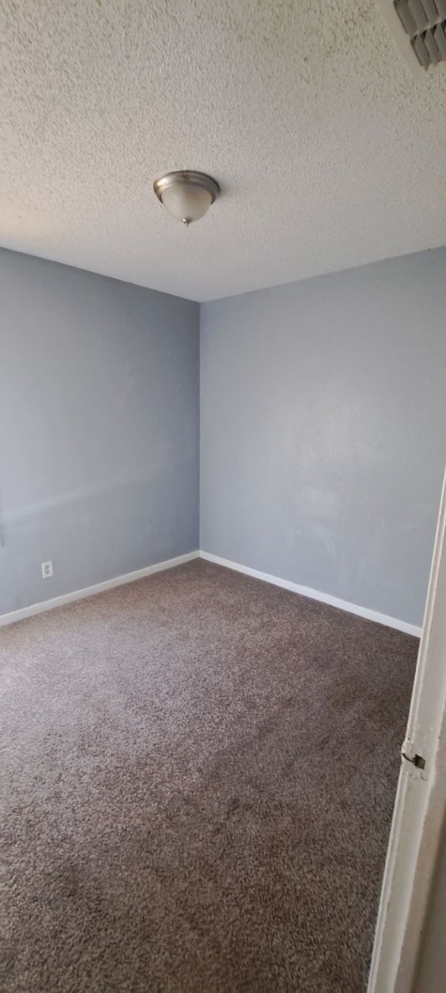 carpeted empty room with a textured ceiling