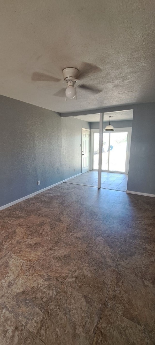 empty room with ceiling fan and a textured ceiling