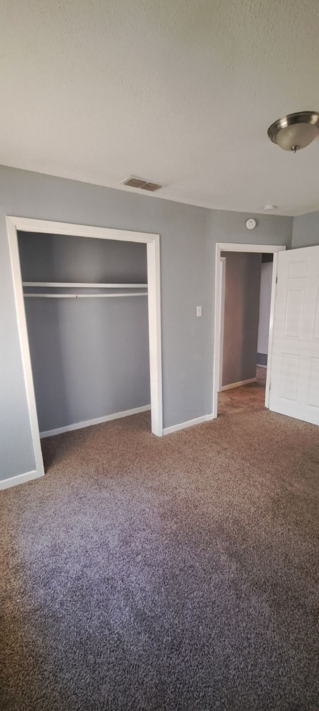 unfurnished bedroom with a closet, a textured ceiling, and carpet floors