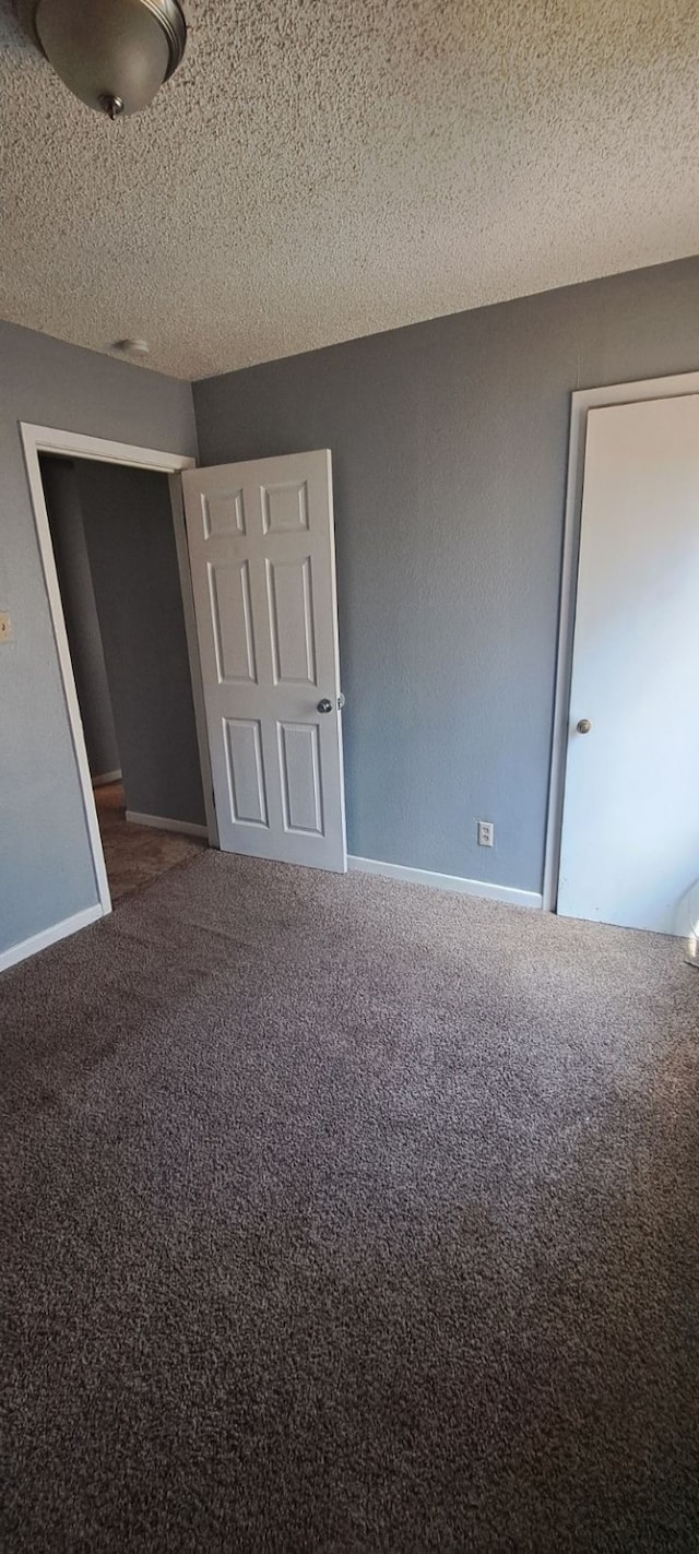 unfurnished bedroom featuring dark colored carpet and a textured ceiling