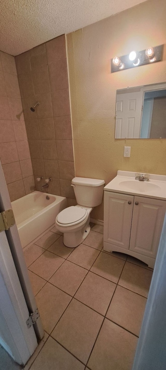 full bathroom with tiled shower / bath, a textured ceiling, toilet, vanity, and tile patterned flooring