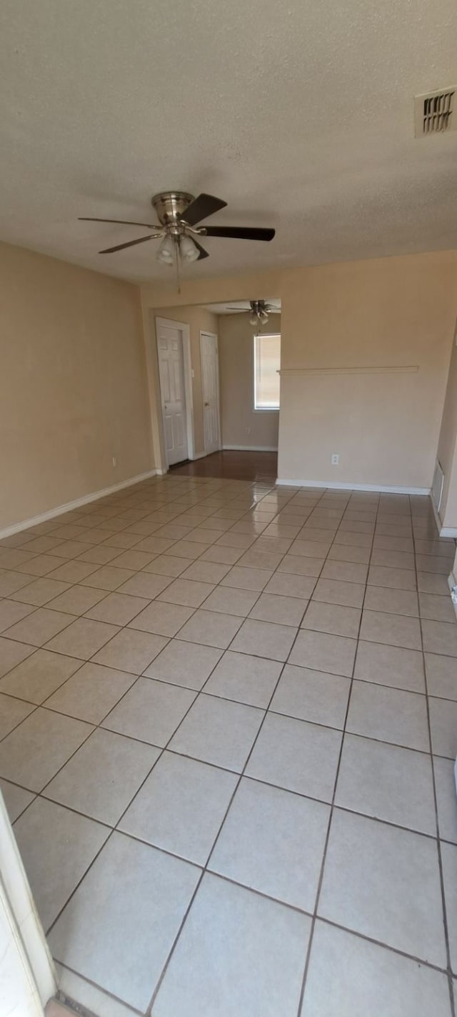 tiled empty room with a textured ceiling and ceiling fan