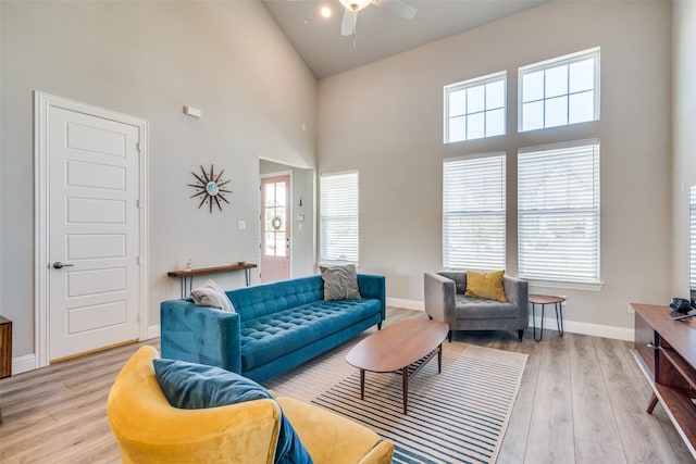 living room featuring a towering ceiling, light hardwood / wood-style flooring, and a wealth of natural light