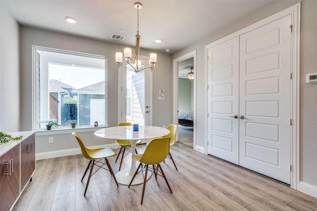 dining space featuring ceiling fan with notable chandelier and light hardwood / wood-style floors