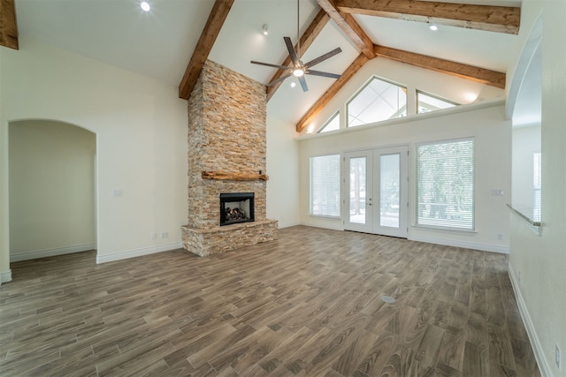 unfurnished living room featuring a stone fireplace, ceiling fan, dark wood-type flooring, beam ceiling, and high vaulted ceiling