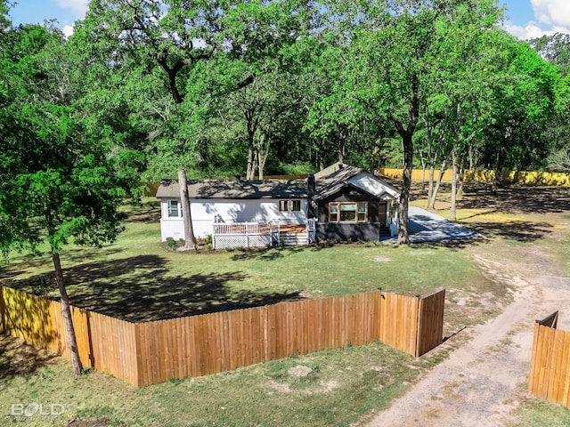 view of front of home featuring dirt driveway, fence, and a front yard