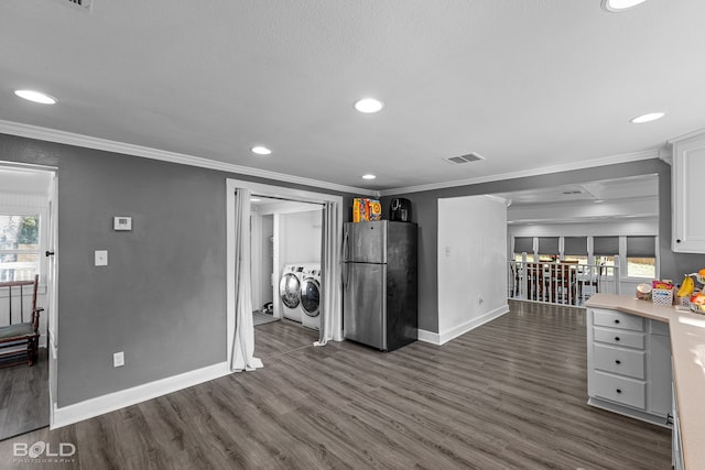 kitchen with dark hardwood / wood-style flooring, stainless steel fridge, white cabinets, ornamental molding, and washer and clothes dryer