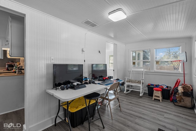 office area featuring wooden walls, wood-type flooring, and vaulted ceiling