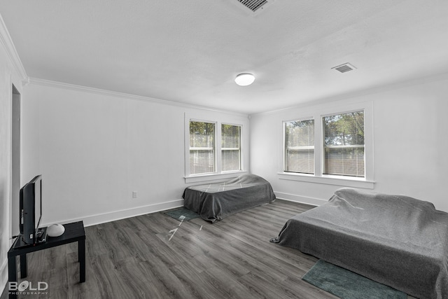 bedroom with ornamental molding, dark wood-type flooring, visible vents, and baseboards