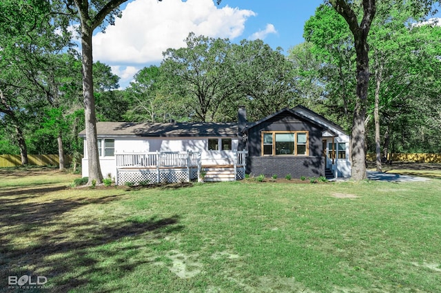 view of front of property featuring brick siding, fence, a deck, and a front yard