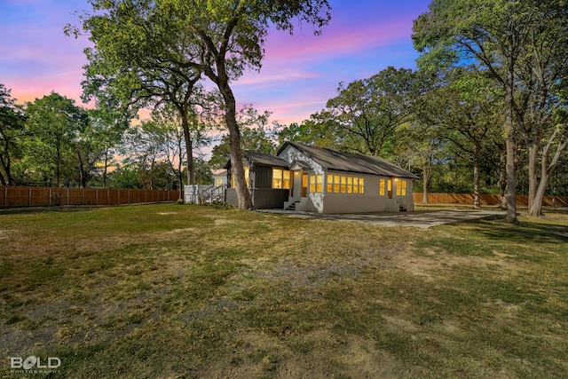 back of property at dusk with a yard, a patio area, and a fenced backyard