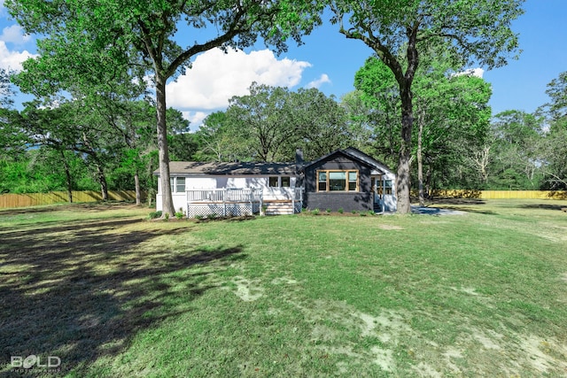 view of front facade featuring a front lawn, a wooden deck, and fence