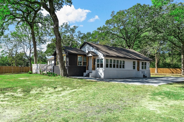 view of front facade featuring concrete driveway, brick siding, fence, and a front lawn