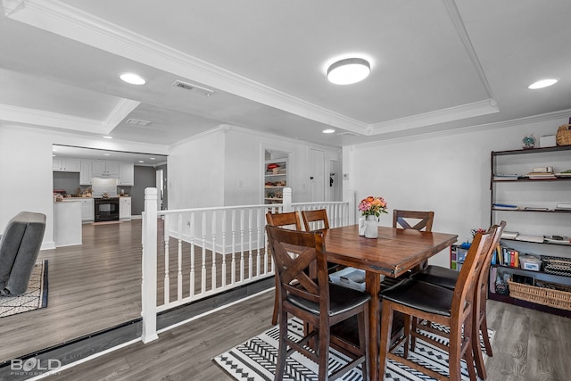 dining room featuring dark wood-style floors, ornamental molding, a raised ceiling, and visible vents