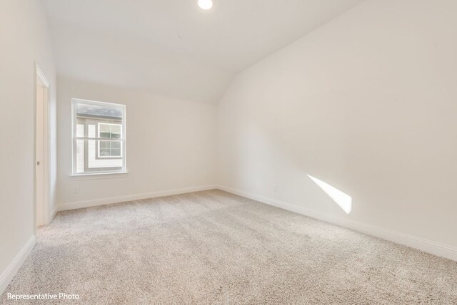 carpeted empty room with vaulted ceiling