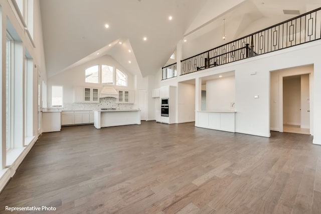 unfurnished living room with wood-type flooring and high vaulted ceiling