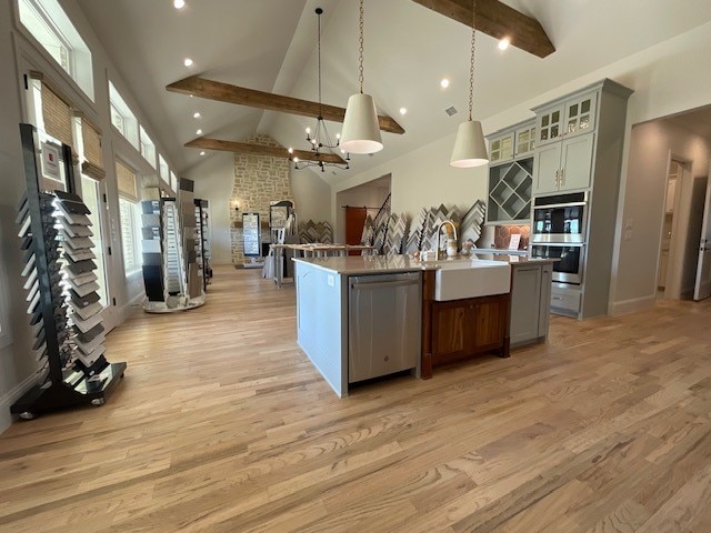 kitchen featuring hanging light fixtures, a center island with sink, sink, appliances with stainless steel finishes, and high vaulted ceiling