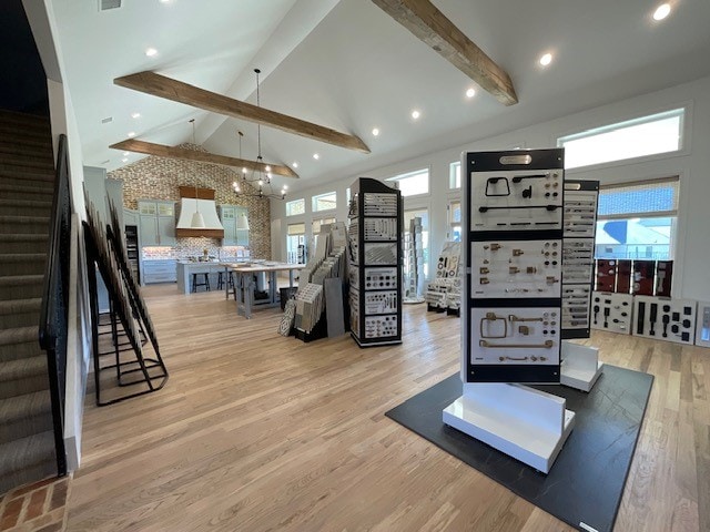 workout area with a chandelier, high vaulted ceiling, and light wood-type flooring