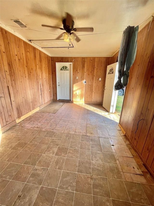 empty room with ceiling fan and wood walls