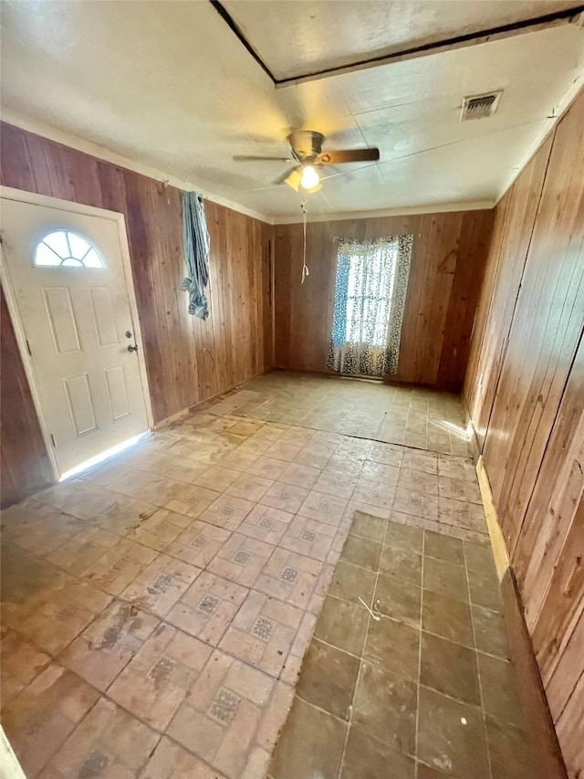 entrance foyer with ceiling fan and wooden walls