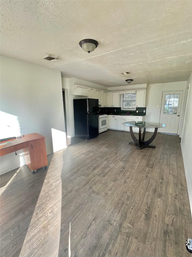 kitchen with dark hardwood / wood-style flooring, white range with gas stovetop, white cabinets, and black fridge