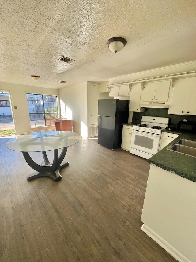 kitchen featuring sink, black refrigerator, white cabinetry, dark hardwood / wood-style flooring, and white gas stove