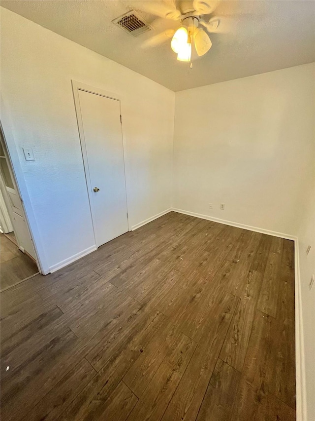 unfurnished bedroom featuring ceiling fan, dark wood-type flooring, and a textured ceiling