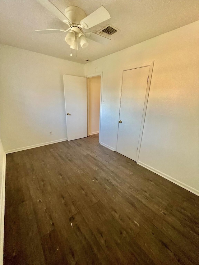 unfurnished bedroom featuring dark wood-type flooring and ceiling fan