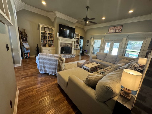 living room featuring french doors, dark wood-type flooring, crown molding, a brick fireplace, and ceiling fan