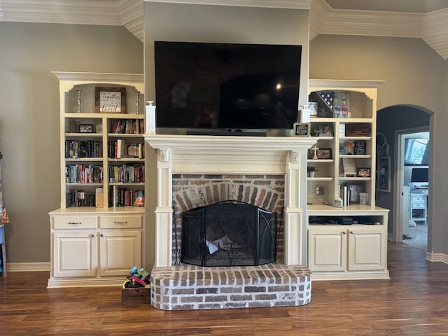 living room with dark wood-type flooring, a brick fireplace, and crown molding