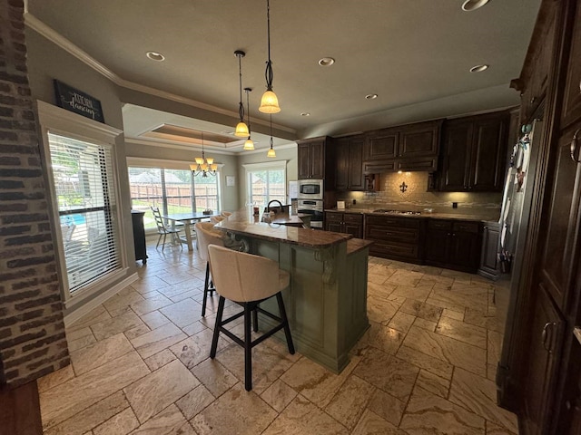 kitchen with decorative backsplash, a kitchen island with sink, hanging light fixtures, a kitchen bar, and appliances with stainless steel finishes