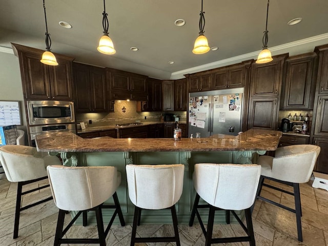 kitchen featuring built in appliances, a breakfast bar, decorative light fixtures, and a large island