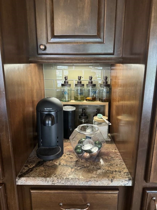 bar featuring decorative backsplash, light stone counters, and dark brown cabinets