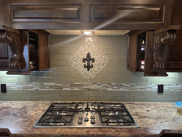 kitchen featuring light stone counters, stainless steel gas cooktop, dark brown cabinets, and tasteful backsplash