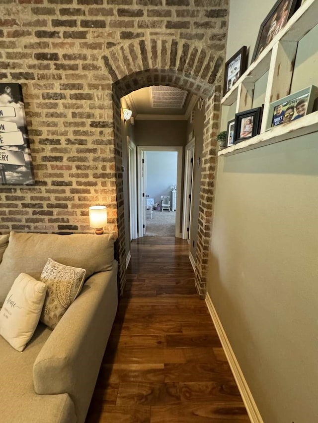 hallway featuring crown molding, brick wall, and dark hardwood / wood-style floors