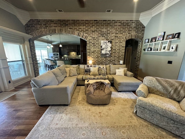 living room featuring brick wall, wood-type flooring, and ornamental molding