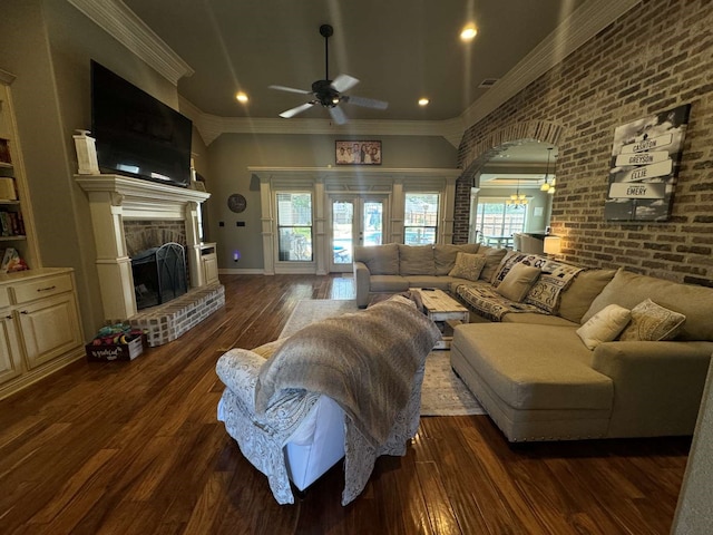 living room with crown molding, a brick fireplace, dark hardwood / wood-style floors, and ceiling fan