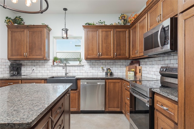 kitchen with pendant lighting, decorative backsplash, sink, and stainless steel appliances