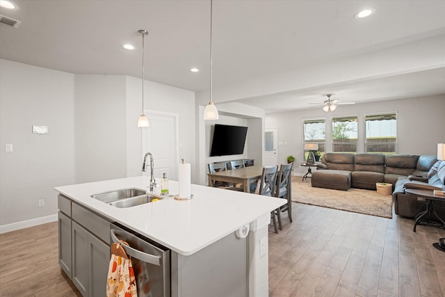 kitchen featuring light hardwood / wood-style floors, stainless steel dishwasher, sink, and pendant lighting