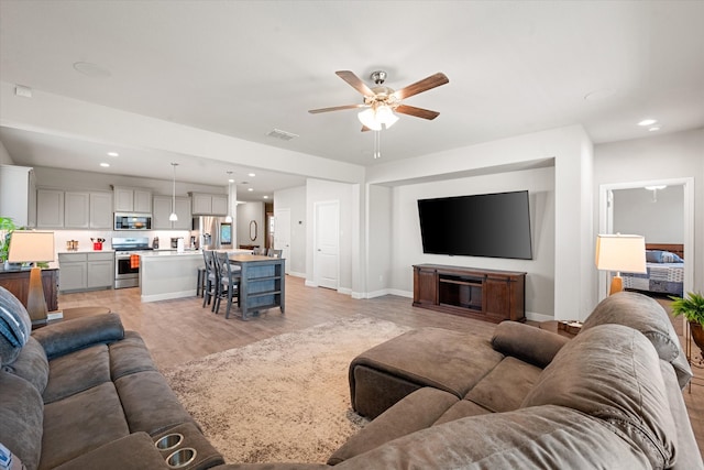 living room featuring light hardwood / wood-style flooring and ceiling fan